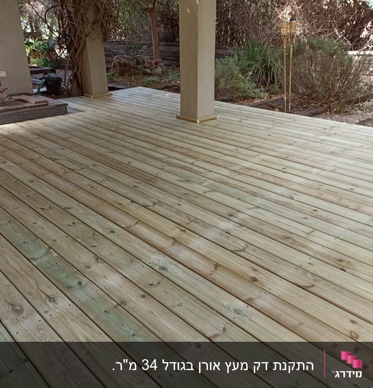דק עץ חדש בגינה עם עמודים ותאורה